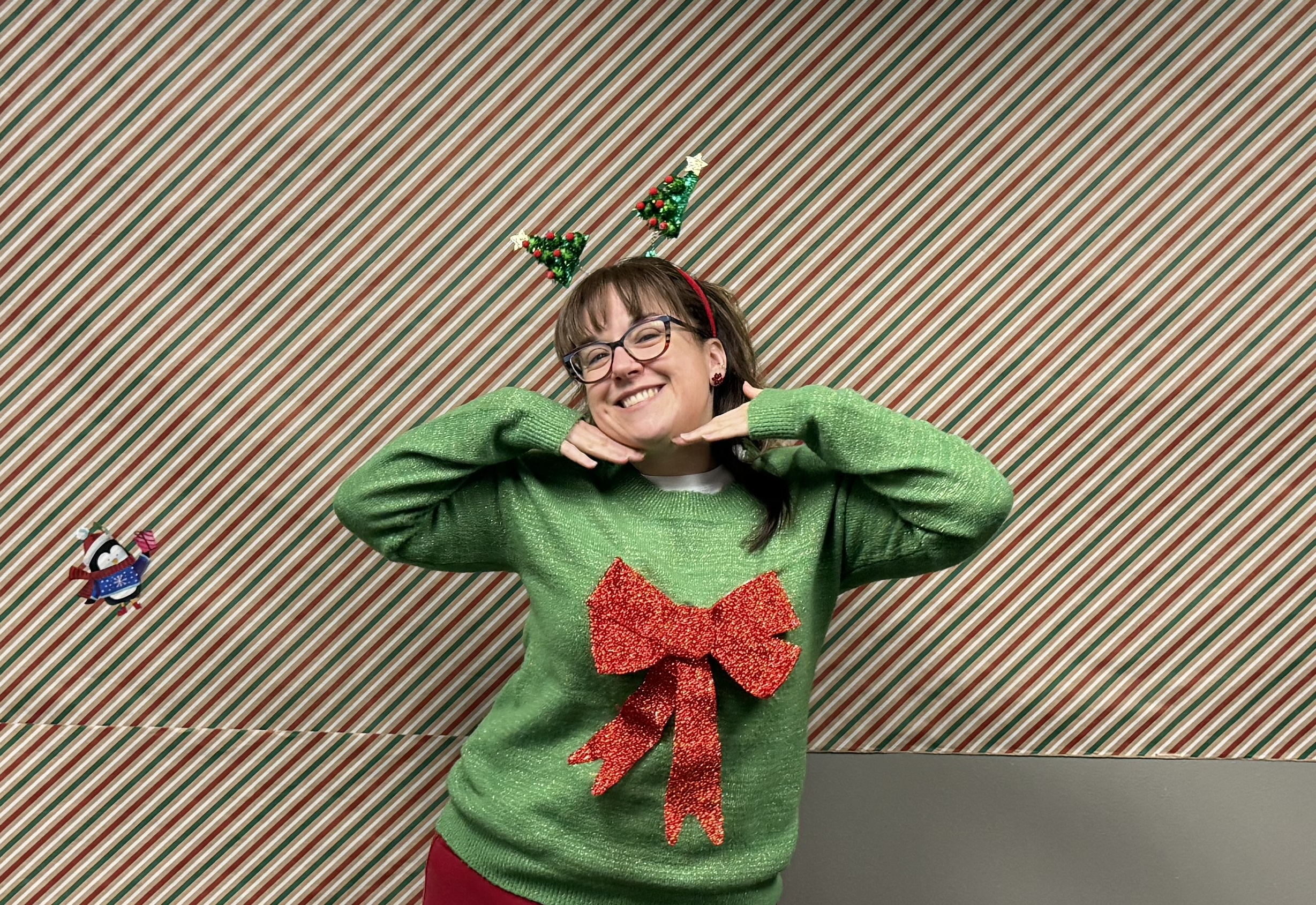 Natasha in a green Christmas sweat with a big red bow on it and Christmas tree antenna headband.