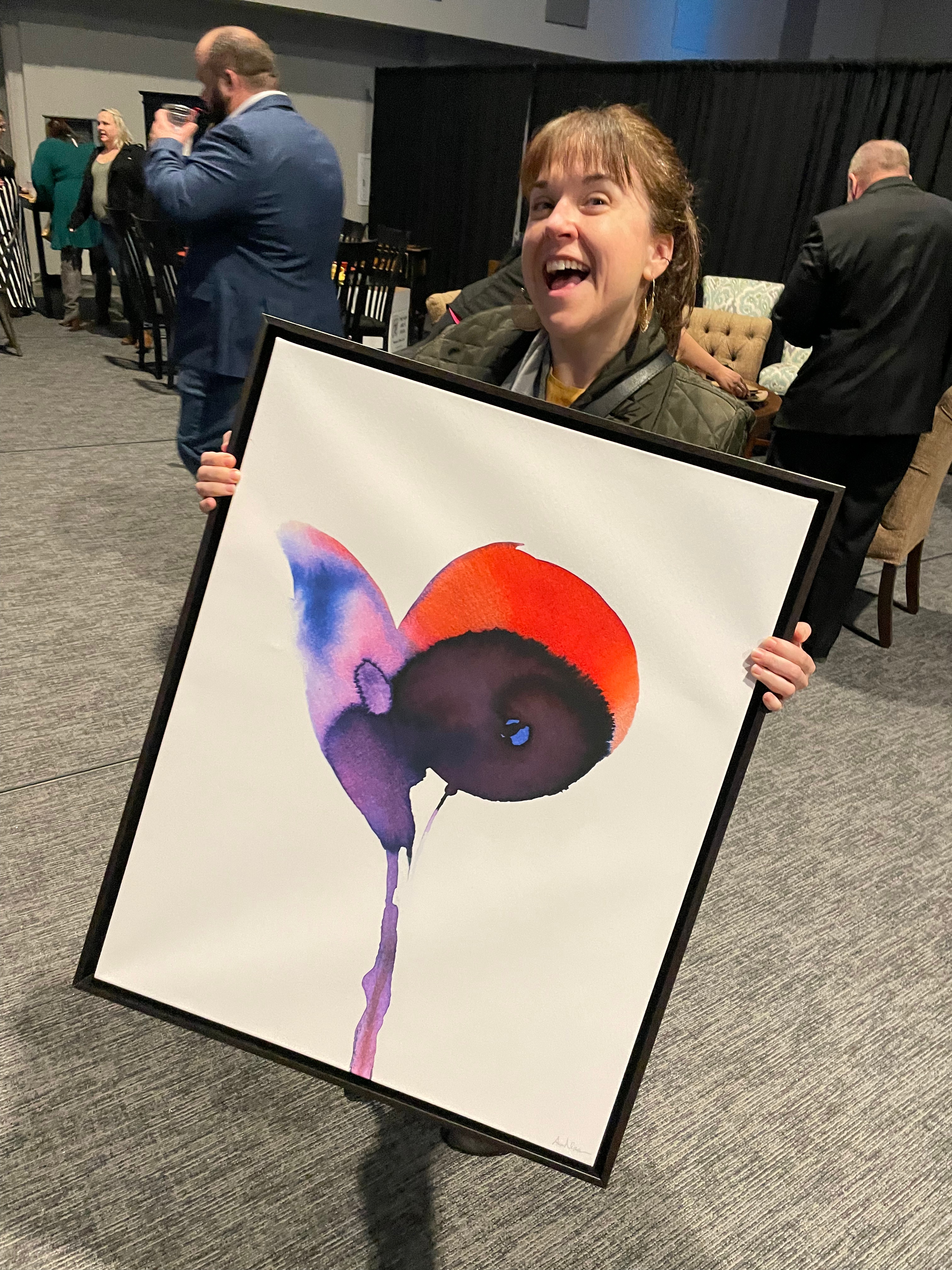 Natasha holding a wall hanging with an abstract flower on it